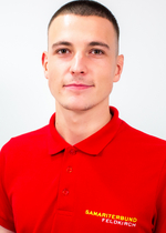 Junger Mann in rotem Polohemd mit einem Logo des Samariterbundes.