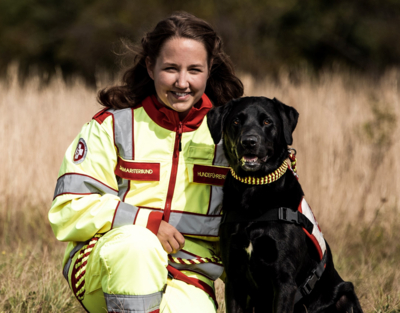 Porträt Hundeführerin in Samariterbund Uniform mit Hund, beide schauen in Kamera