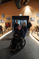 Gruppe von Menschen in einem Fahrradmuseum, einschließlich einer Person im Rollstuhl.