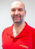 Mann mit kurzem Bart trägt ein rotes Polo-Shirt mit Logo des Samariterbundes.