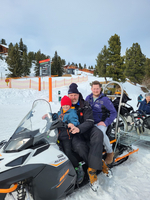 Vater und Sohn fahren zusammen auf einem Schneemobil im Schnee.