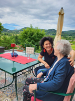 Zwei Frauen sitzen gemütlich an einem Tisch im Freien und unterhalten sich.