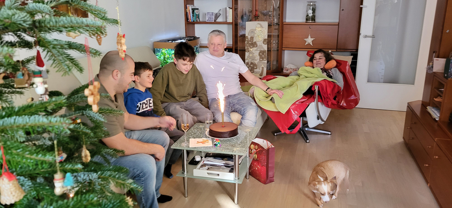 Familie feiert Weihnachten im Wohnzimmer mit einem Kuchen und Geschenken.