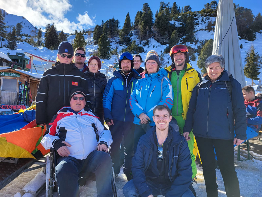 Eine Gruppe von zehn Personen in Skikleidung steht im Schnee.