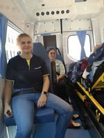 Zwei Frauen sitzen in einem Sanitätsfahrzeug, eine lächelt.