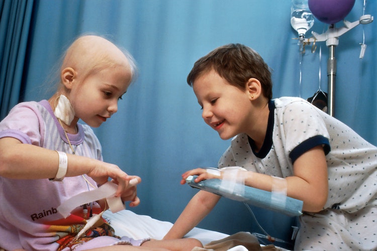 Zwei schwerkranke Kinder unterhalten sich fröhlich auf einem Krankenhausbett